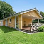 A yellow house with a porch and garden. Wooden terrace with white railings.