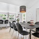 Dining area with black chairs and table. Kitchen in background with windows.