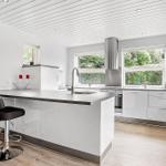 Modern kitchen with island, black bar stools, and windows to the garden.