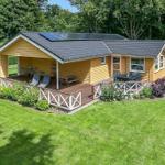 A yellow vacation home with terrace, garden, and solar panels on the roof.
