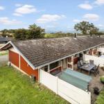 Red house with terrace and garden. View of water and green areas.