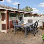 Patio with table, chairs, and grill. Backyard with white fence and garden.