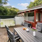 Terrace with table, chairs, and swing under a green sky.