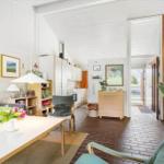 Living area with dining space and kitchen. Wooden floor and white walls.