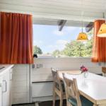 Kitchen with dining table, window, and orange curtains.