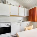Kitchen with white cabinets, sink, and dining area with table and chairs.