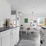 Kitchen with dining area, window, white furniture and dark countertops.