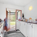 Kitchen with white cabinets, dark countertop, and door to the garden.