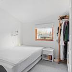 Bedroom with bed, clothes rack, and window.