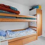 Room with bunk bed, wardrobe, and window with view of outside area.