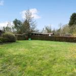 Green lawn area with playground and trees in the background.