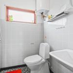 Bathroom with toilet, sink, and shower. Window with wooden frame.