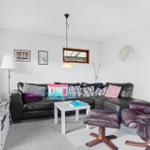 Living room with black leather sofa, wooden chair, and TV