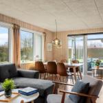 Living and dining area with sofa, table and chairs. Large windows and glass door to the garden.