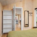 Bedroom with wooden walls, bed, mirror, and door to hallway.