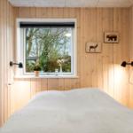 Bedroom with wooden walls, window, and bed. Animal pictures hang on the walls.