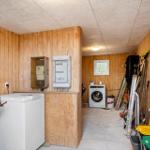 Room with washing machine, tools, and trash bins against walls.