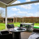 Deck with seating and view of garden with swing and kayak.