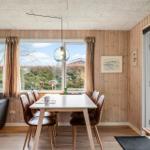 Dining area with table, chairs, and sofa. Wooden walls, large windows, and glass door.