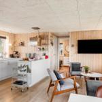 Living kitchen with wooden walls, TV, sofa, and sink.