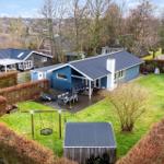 Blue house with terrace, garden, and swing set.