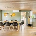Dining area with table, chairs, and wood-burning stove. Wooden ceiling and windows with green view.