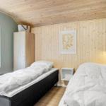 Two beds in a room with wooden wall and window.