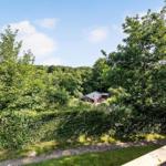House surrounded by trees and shrubs, with a view of the forest.