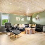 Living room with black leather sofa, wooden table and chair. Wooden ceiling and green walls.