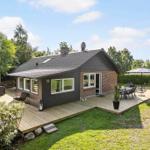 Wooden terrace with seating around a house with garden and trees.