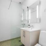 Shower with glass enclosure, sink and toilet in white finish.
