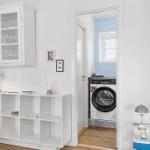 Living area with cabinet, side table, and view into laundry room with washing machine.
