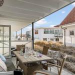 Terrace with table, chairs, and bench. View of white houses and grass.
