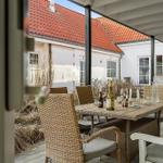 Terrace with dining table and chairs, view of white buildings with red roofs.