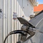 Electric car charging at wall socket. Sign indicates private parking.