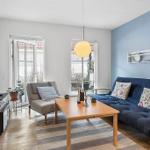Living room with sofa, armchair, coffee table, and TV. Blue wall and windows to terrace.