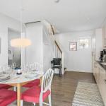 Dining area with table and chairs, kitchen and staircase in background.