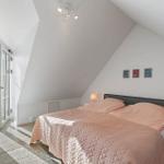 Bedroom with sloped ceiling, bed, and balcony access.