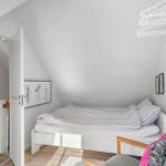 Bedroom with bed, chair, and wall art under sloped ceiling.