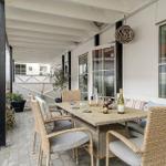 Patio with table, chairs, and drinks under cover.