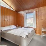 Bedroom with wooden walls, bed, window, and wardrobe.