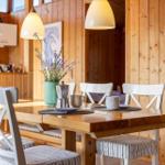 Dining room with wooden table, white chairs, and lavender flowers.
