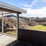 Deck with view of dunes and grassy areas under blue sky.