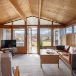 Living room with wooden walls, sofa, TV, and view of the landscape.