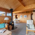 Living room with fireplace, sofa, and dining area. Wooden walls and ceiling.