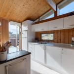 Kitchen with white cabinets, wooden walls, and windows to the balcony.