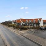 A holiday home complex with red roof and parking lot along the road.