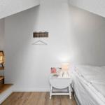 Bedroom with sloped ceiling, bed, nightstand, and lamp.