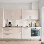 Modern kitchen with light cabinets, stainless steel appliances, and large window.