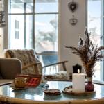 Round table with candle, dried plant, and book in living room with seating.